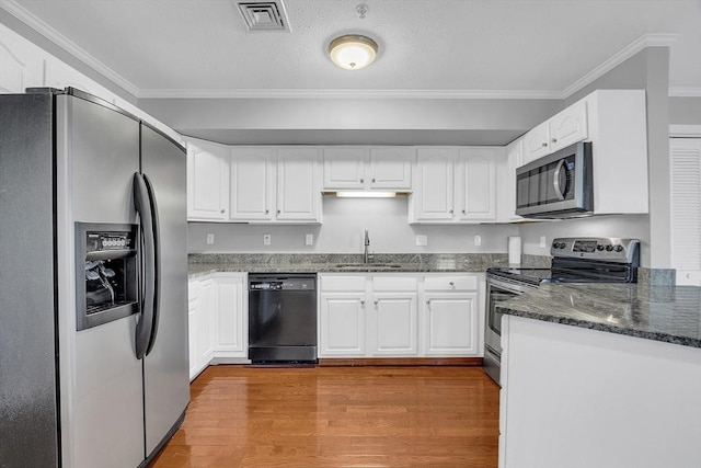 kitchen featuring white cabinets, appliances with stainless steel finishes, light hardwood / wood-style floors, and crown molding