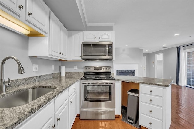 kitchen featuring light wood-type flooring, stainless steel appliances, white cabinetry, and sink