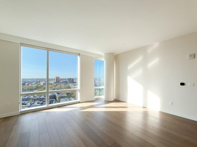 empty room with wood finished floors, baseboards, and a city view