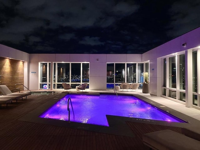 pool at twilight with a wooden deck and an outdoor pool