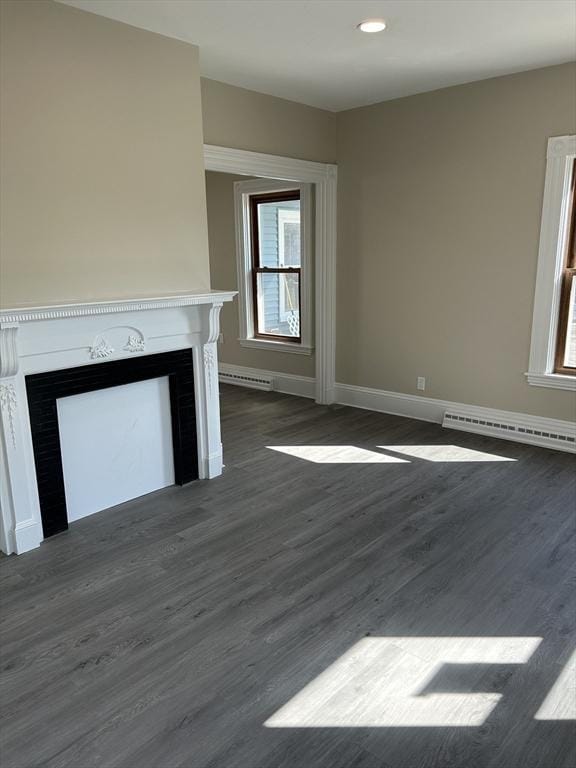 unfurnished living room featuring a baseboard heating unit, baseboards, dark wood-style flooring, and a fireplace