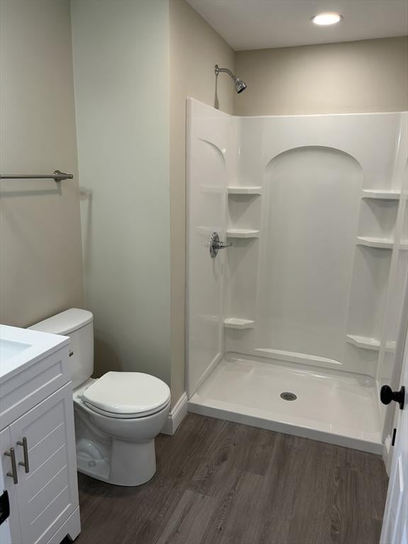 full bathroom featuring toilet, wood finished floors, vanity, and a walk in shower