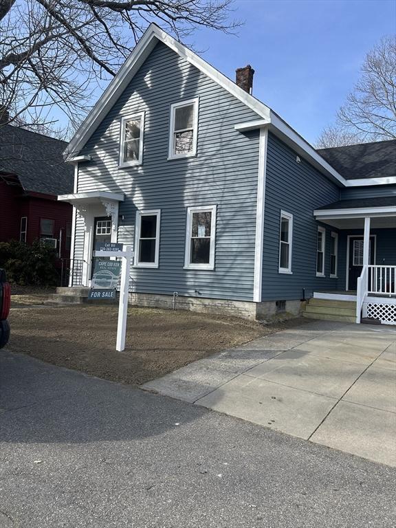 view of side of home with covered porch and a chimney