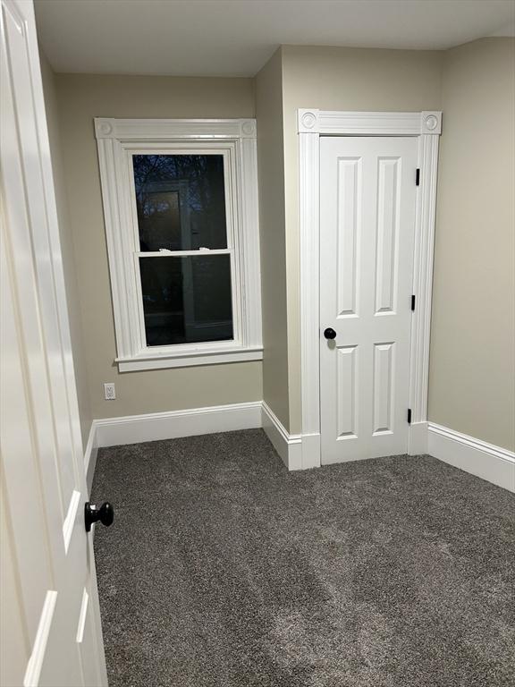 carpeted spare room featuring baseboards