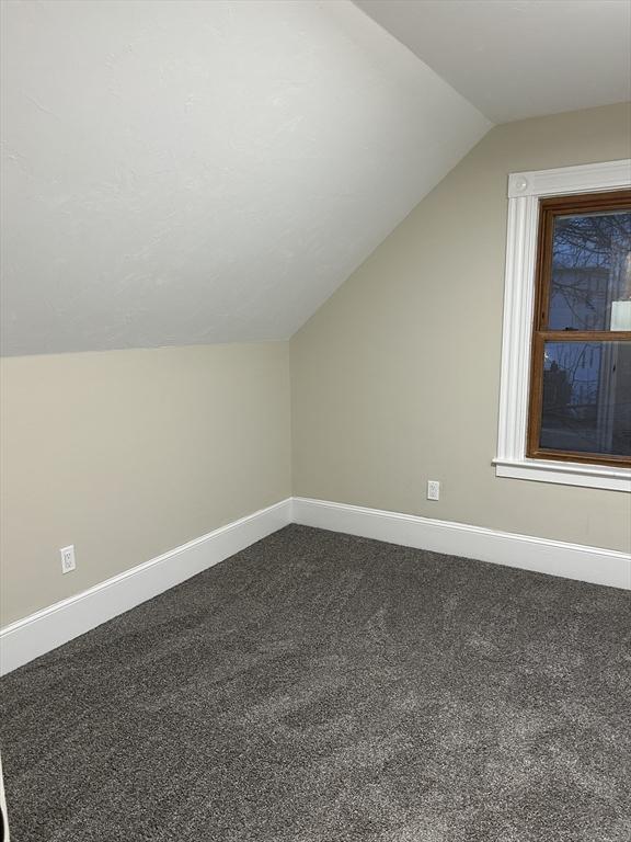 bonus room featuring lofted ceiling, baseboards, and dark colored carpet