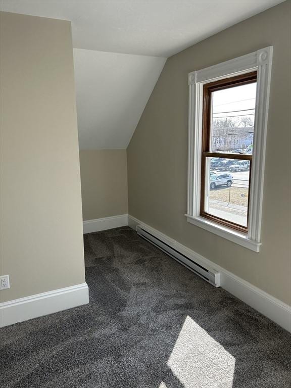 additional living space featuring a baseboard heating unit, lofted ceiling, baseboards, and dark colored carpet