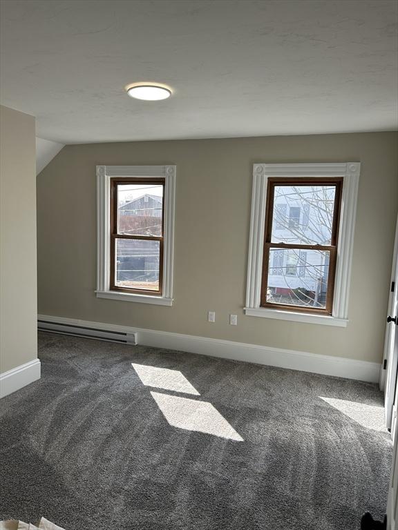 additional living space with a baseboard radiator, a healthy amount of sunlight, and carpet flooring