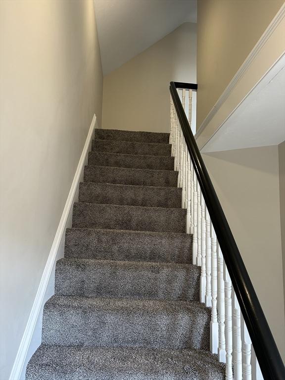 staircase with lofted ceiling and baseboards