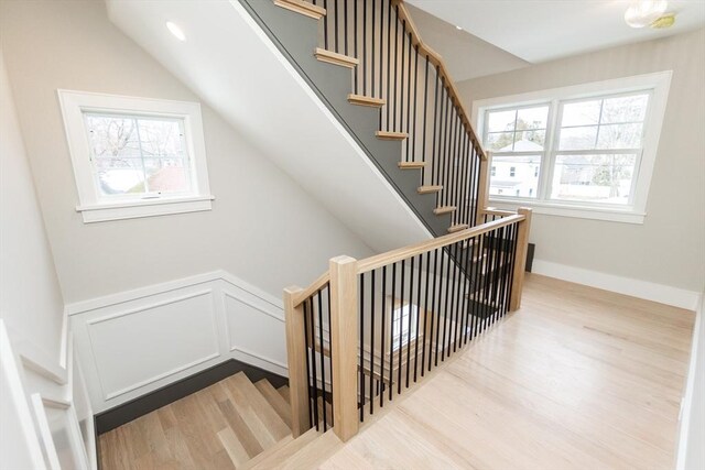 stairway with wood finished floors, a wealth of natural light, and baseboards