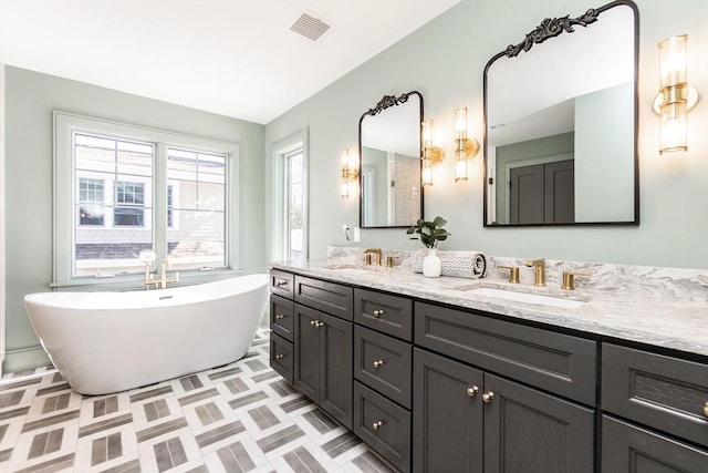 bathroom featuring visible vents, a sink, a freestanding bath, and double vanity