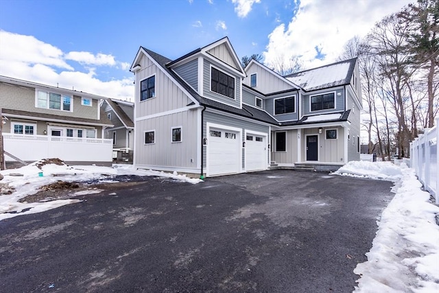 view of front of home featuring aphalt driveway, fence, board and batten siding, and an attached garage