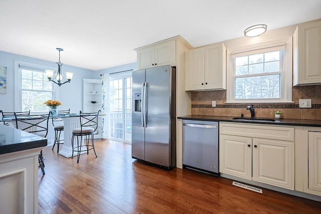 kitchen with plenty of natural light, stainless steel appliances, dark countertops, and dark wood-style floors