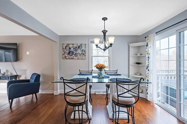 dining room with a healthy amount of sunlight, a notable chandelier, baseboards, and wood finished floors