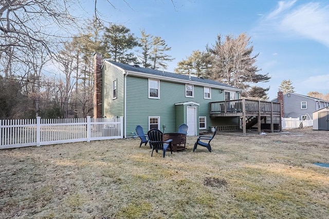 back of house with an outdoor fire pit, a fenced backyard, a chimney, an outbuilding, and a wooden deck