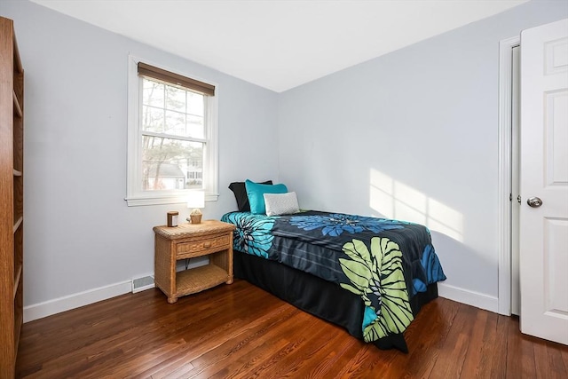 bedroom with visible vents, baseboards, and wood finished floors