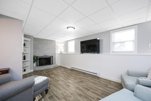 living room featuring a baseboard radiator, a large fireplace, a paneled ceiling, and wood finished floors