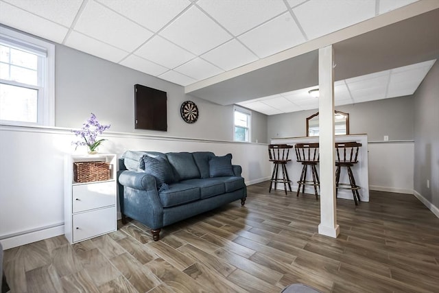 living room featuring a paneled ceiling, a bar, and wood finished floors