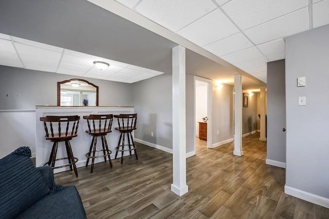 interior space with a dry bar, wood finished floors, and a paneled ceiling