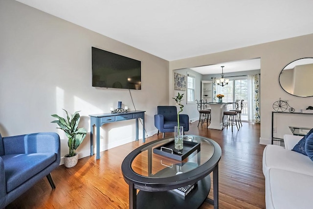 living area with a notable chandelier, baseboards, and wood finished floors