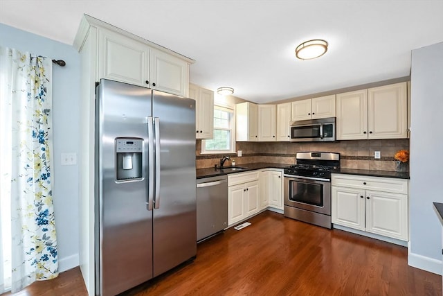 kitchen featuring dark countertops, dark wood-style floors, appliances with stainless steel finishes, and decorative backsplash