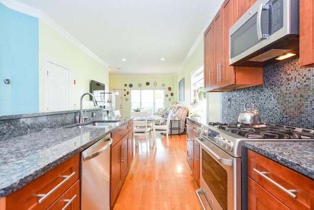 41 Oak St Unit 2, Waltham, MA 02453 - kitchen featuring appliances with stainless steel finishes, brown cabinets, light wood-style floors, dark stone counters, and backsplash