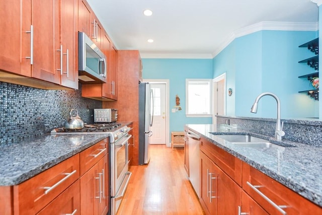 41 Oak St Unit 2, Waltham, MA 02453 - kitchen with appliances with stainless steel finishes, brown cabinetry, light wood-type flooring, dark stone counters, and crown molding