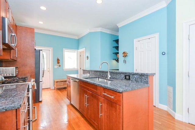 41 Oak St Unit 2, Waltham, MA 02453 - kitchen with appliances with stainless steel finishes, light wood-type flooring, brown cabinets, a kitchen island with sink, and dark stone counters