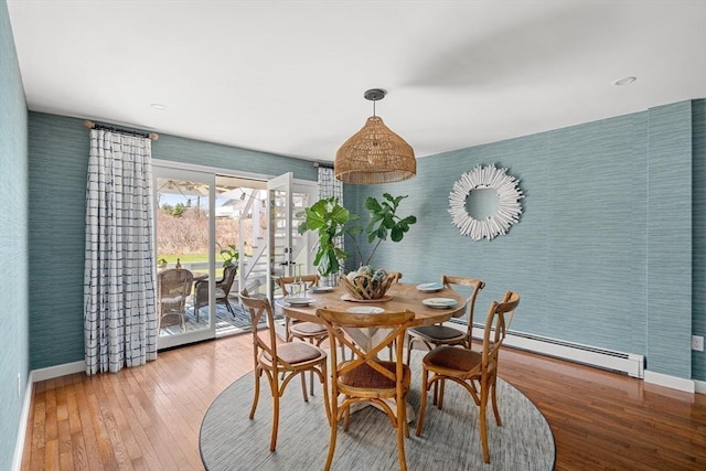 dining room featuring baseboards, a baseboard heating unit, hardwood / wood-style flooring, and wallpapered walls