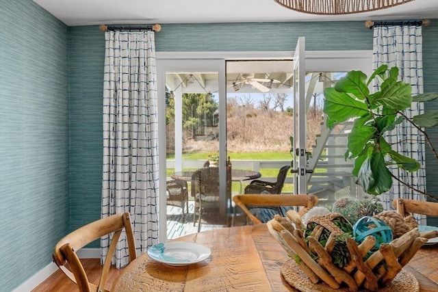 doorway featuring baseboards, ceiling fan, wood finished floors, and wallpapered walls