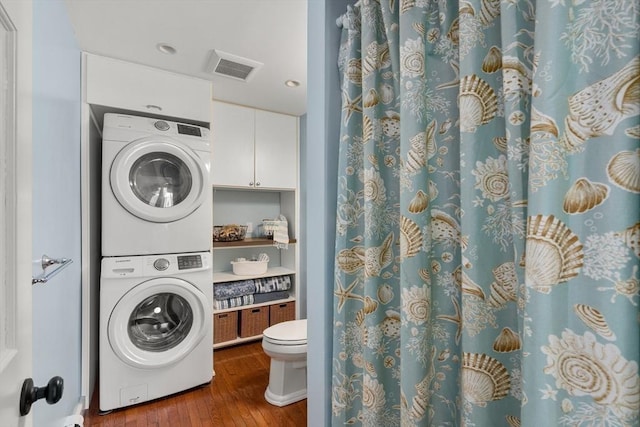 bathroom with wood-type flooring, stacked washer and clothes dryer, visible vents, toilet, and a shower with curtain