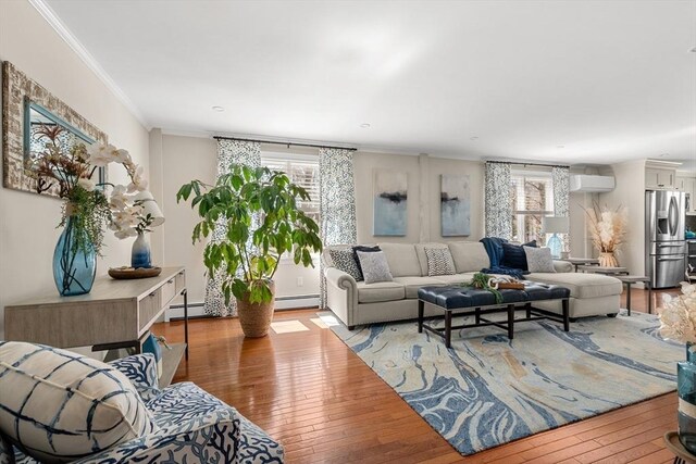 living area with a wall mounted AC, ornamental molding, baseboard heating, and light wood-type flooring