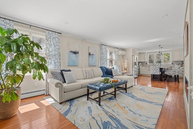 living room with plenty of natural light, baseboard heating, and light wood-type flooring