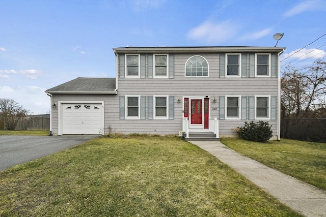 colonial inspired home featuring a garage and a front lawn