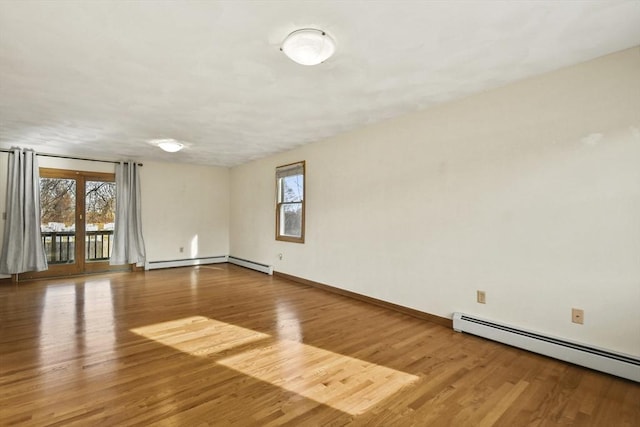 unfurnished room featuring a healthy amount of sunlight, a baseboard radiator, and hardwood / wood-style flooring