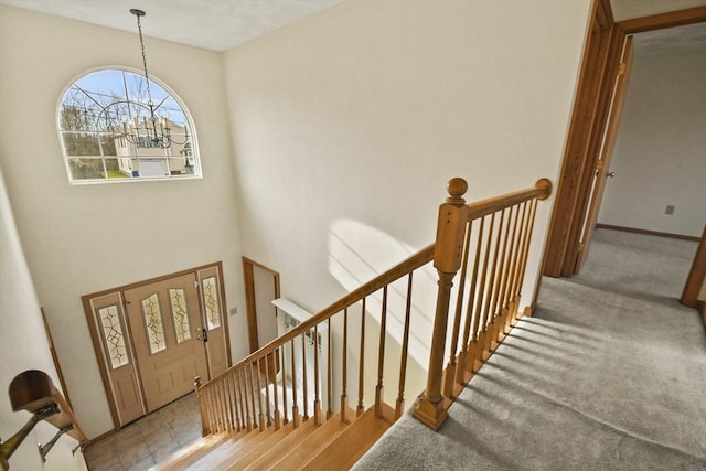 entryway with a towering ceiling, light carpet, and a chandelier