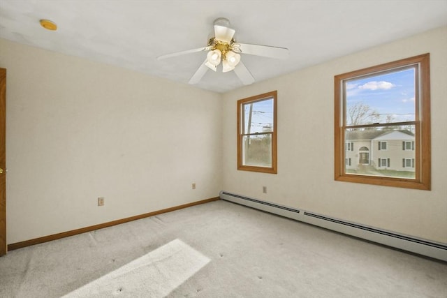 carpeted empty room with ceiling fan, plenty of natural light, and a baseboard heating unit