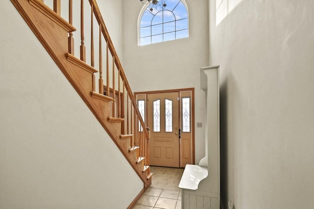 tiled foyer with a towering ceiling, a wealth of natural light, and a chandelier