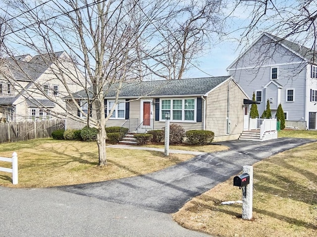 view of front of home featuring a residential view, roof with shingles, a front lawn, and fence