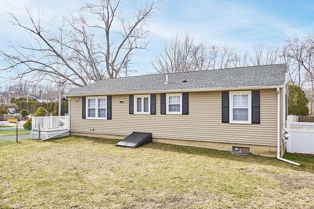 view of front of home with roof with shingles, a front yard, and fence