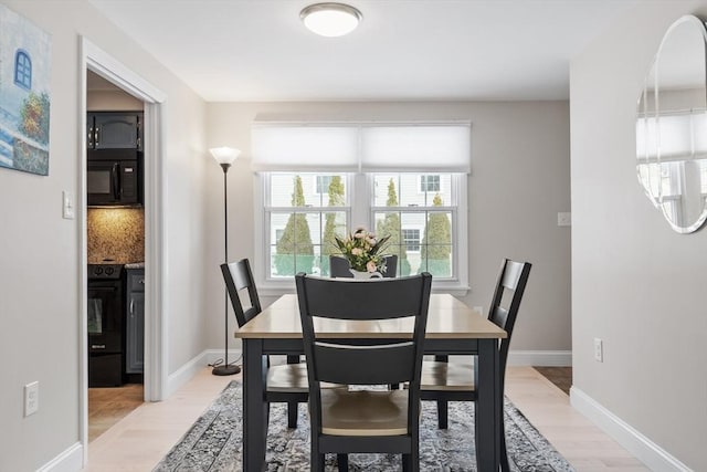 dining area with baseboards and light wood-style flooring