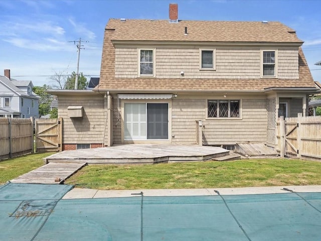 rear view of property featuring a deck, a gate, a gambrel roof, a shingled roof, and a chimney