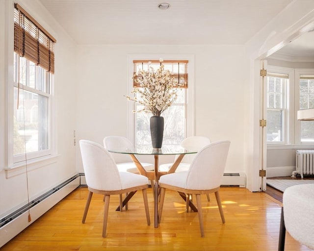 dining space featuring light wood-type flooring, radiator heating unit, and baseboard heating