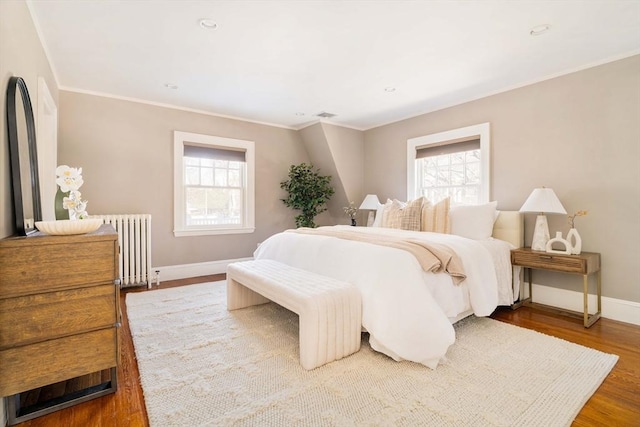 bedroom featuring hardwood / wood-style flooring, ornamental molding, and radiator