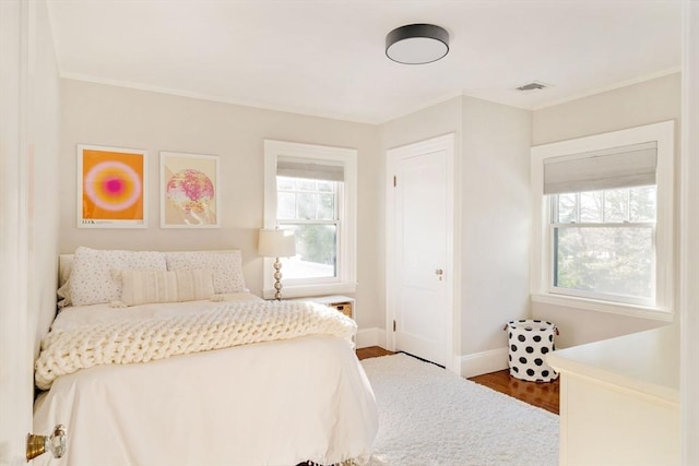 bedroom featuring crown molding, wood-type flooring, and multiple windows