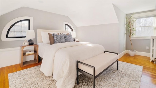 bedroom featuring multiple windows, vaulted ceiling, and light hardwood / wood-style floors