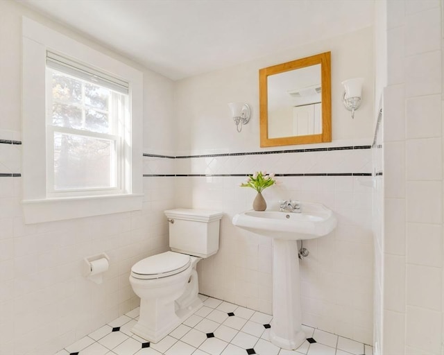 bathroom with tile patterned flooring, sink, tile walls, and toilet