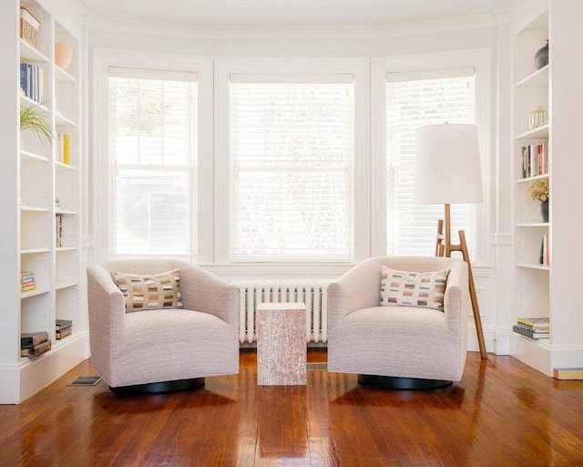 sitting room featuring ornamental molding, radiator heating unit, wood-type flooring, and built in features