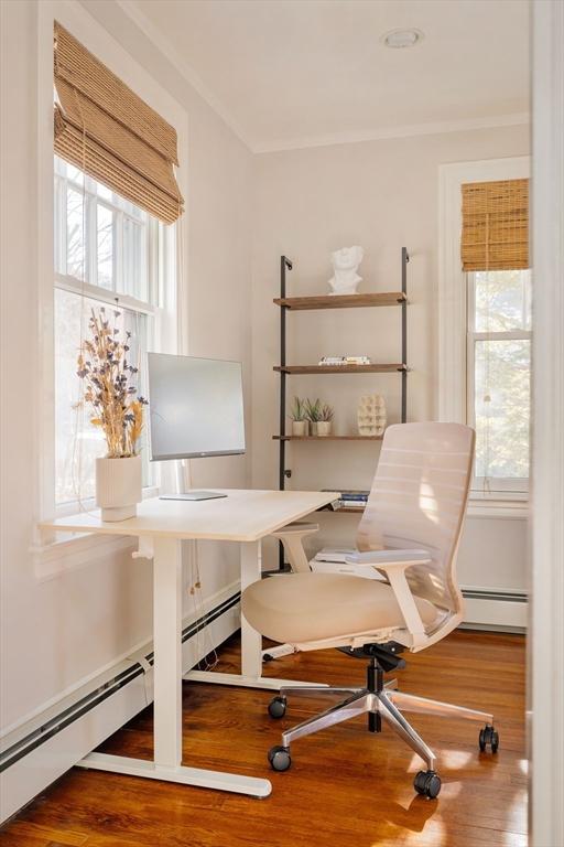 office space featuring hardwood / wood-style flooring, plenty of natural light, and a baseboard radiator