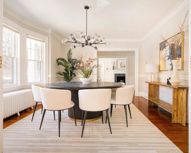 dining area featuring hardwood / wood-style flooring, crown molding, radiator, and a chandelier