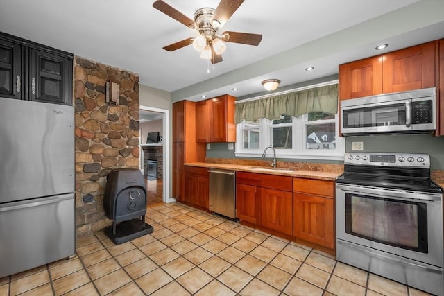 2 Howard St, Braintree, MA 02184 - kitchen with stainless steel appliances, a wood stove, ceiling fan, and brown cabinetry
